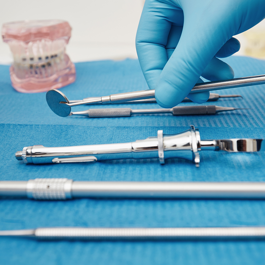 Set of metal medical equipment tools for teeth dental care. Doctor takes medical instruments. Hand of dentist reaching for dental instruments in a cabinet
